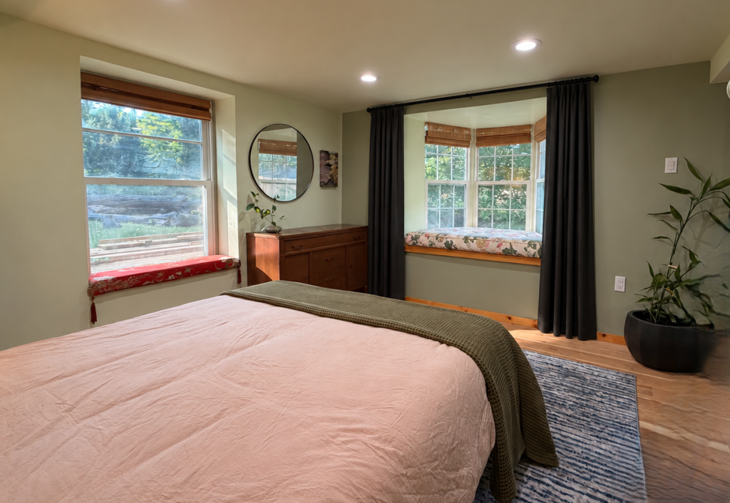 The finished bedroom with soft green walls, warm oak floor and layered lighting.