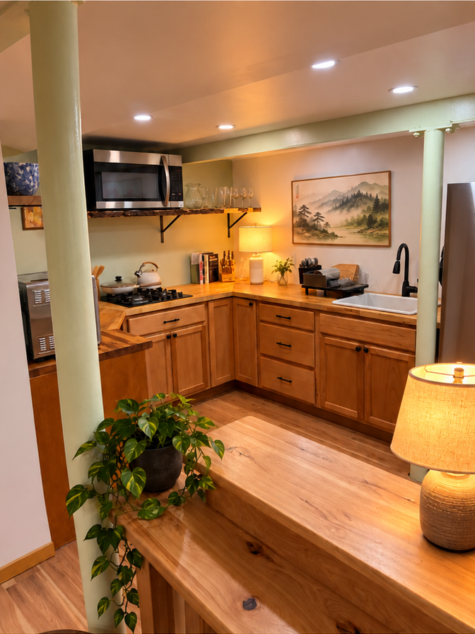A kitchen in warm wood: butcher-block counters, live-edge shelving, solid-wood cabinetry and a lamp lighting the counter.