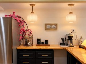The coffee bar: an antique cabinet cut and rebuilt around a support column, painted black, lit by Japanese-inspired pendants.