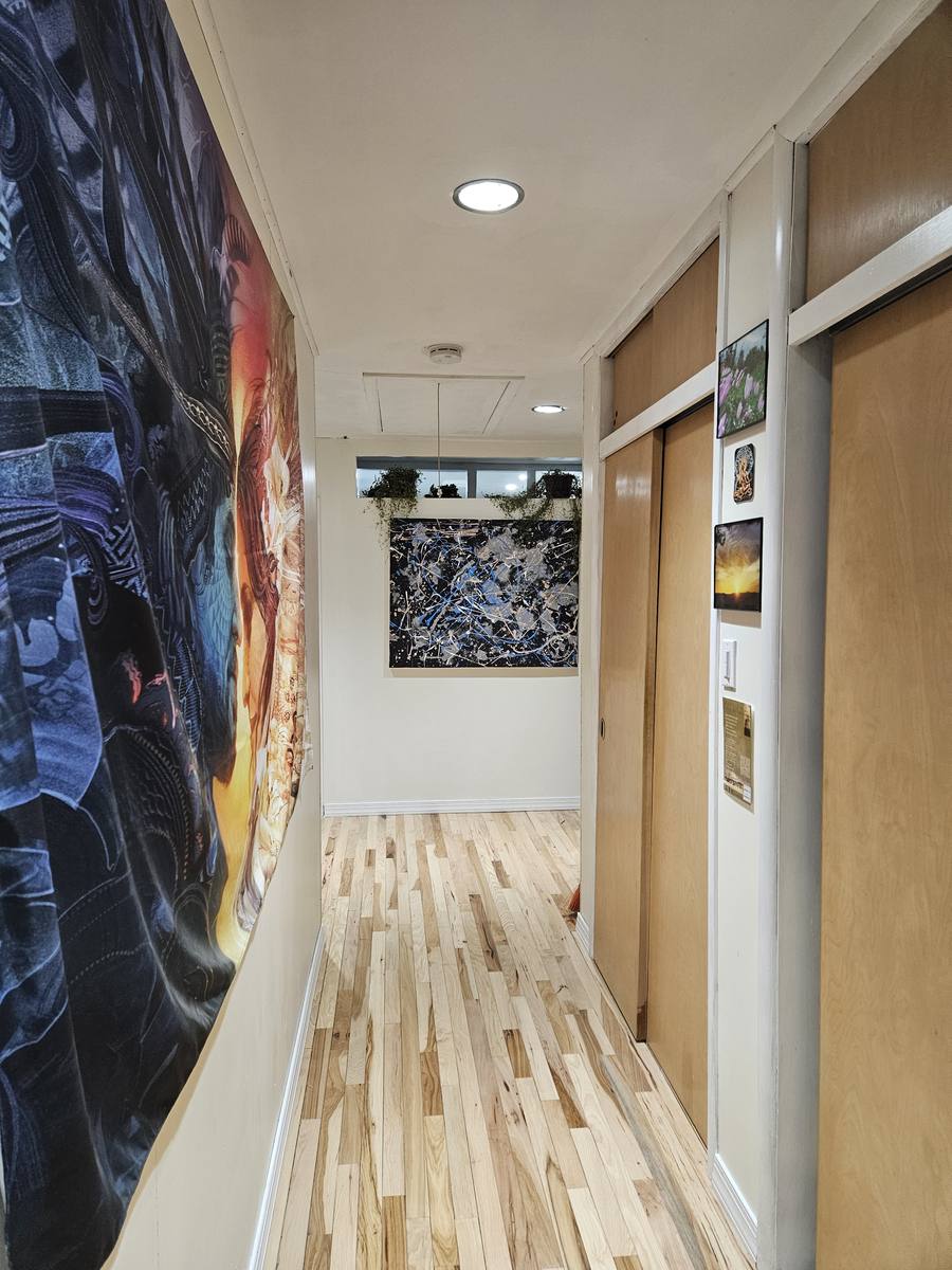 A hallway finished in pale wood, with a large framed artwork and wood doors along one side.